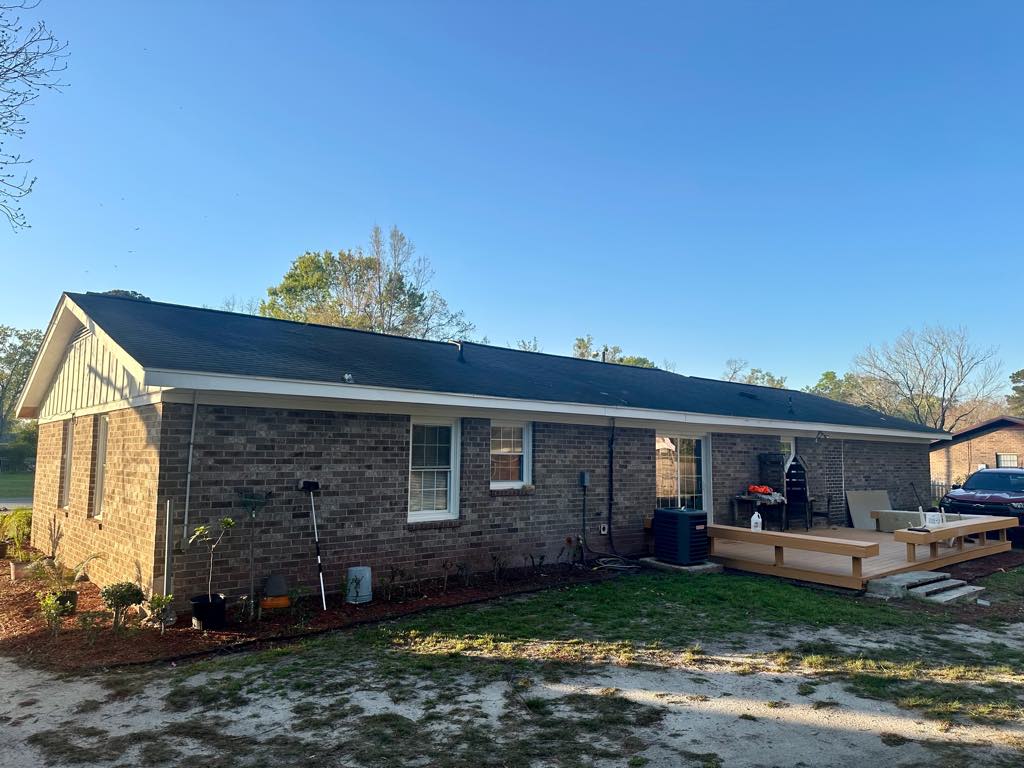 A brick ranch home before the work, with its original dark shingle roof